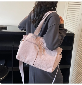 Detail of mauve nylon tote bag featuring unique pleated texture and functional zip pockets