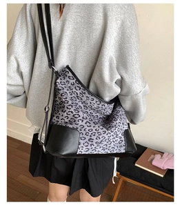 Detailed view of leopard print shoulder bag with black leather base and adjustable strap