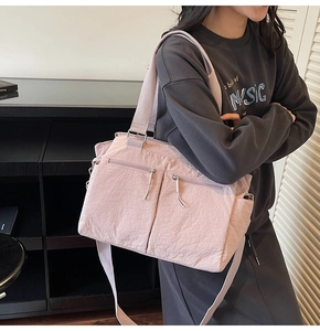 Detail of mauve nylon tote bag with dual front zippers and wide adjustable strap