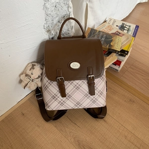 Detail of vintage plaid backpack featuring brown leather flap and cute rabbit charm