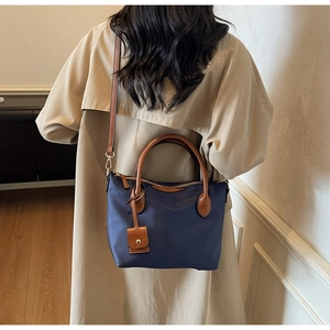 Dettaglio della borsa a secchiello in nylon blu con tracolla e manico in pelle marrone