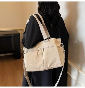 Rear view of a large beige canvas tote bag with multiple pockets worn by a model