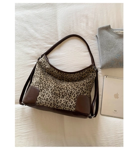 Close-up of leopard print hobo bag with brown faux leather trim and long strap