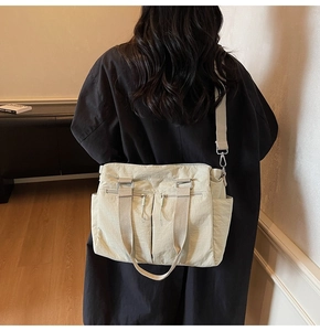 Detail view of large beige canvas tote bag with adjustable straps and front zip pockets