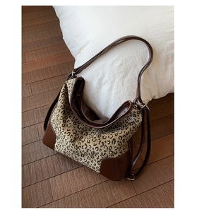 Detailed close-up of leopard print canvas tote bag with dark brown leather straps and base