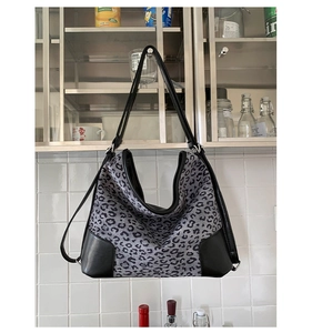 Detail of leopard print tote bag with black leather reinforced corners and trim