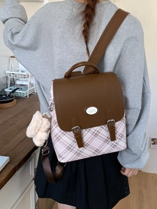 Retro plaid backpack with Cinnamoroll logo and plush charm worn by model in a room