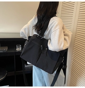 Close-up of functional double zipper pockets on black nylon crossbody bag with silver hardware