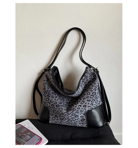 Detail of grey leopard print fabric with black leather corner reinforcement on hobo bag