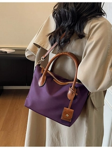 Borsa a secchiello in nylon viola scuro con manici in pelle marrone e tracolla regolabile