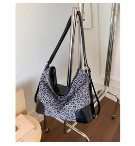 Detail view of leopard print tote bag with black faux leather trim and adjustable strap