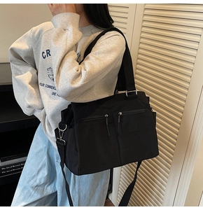 Detail of black canvas tote bag with dual front zipper pockets and adjustable strap