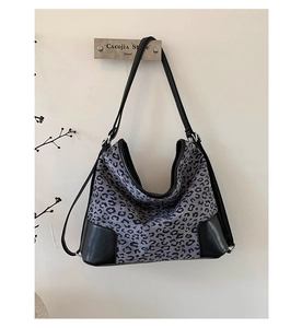 Detail of gray leopard print hobo bag with black leather reinforced base and thin strap
