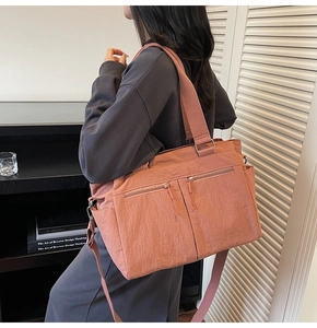 Detailed shot of pink nylon tote bag with functional zippers and wide shoulder strap