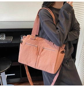 Close-up of coral pink multi-pocket tote bag showing water-resistant nylon texture and straps