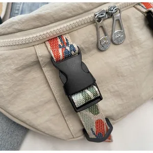 Detailed close-up of beige nylon chest bag with dual metal zippers and colorful webbing