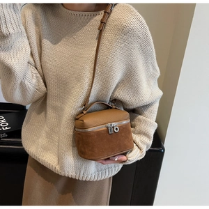 Detail of a brown bucket bag showing lychee grain leather and suede stitching textures