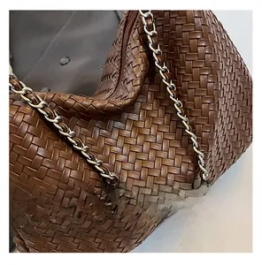 Détails du cuir tressé marron foncé et de la chaîne argentée sur un sac à bandoulière chic