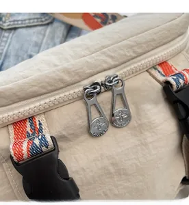 Detail showing smooth double metal zippers and ethnic patterned straps on beige canvas bag