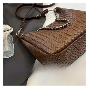 Détail du tissage en cuir marron foncé avec chaîne en métal argenté et bandoulière en cuir