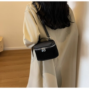 Model wearing a black leather mini vanity crossbody bag with a beige trench coat