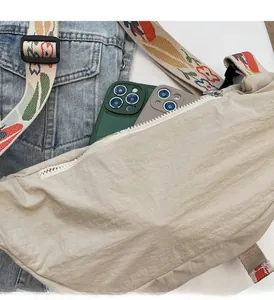 Capacity demonstration of beige nylon moon bag showing internal space for smartphones