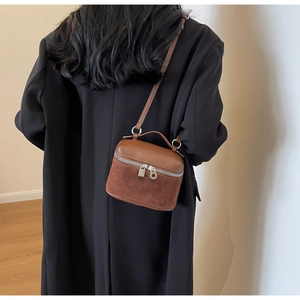 Detail of reddish-brown crossbody bag showing textured leather and suede patchwork
