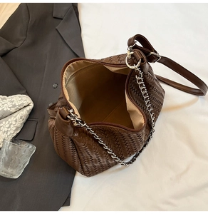 Vue détaillée de la texture tressée du sac avec chaîne argentée et poche intérieure brune