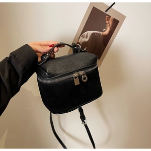 Detail of black leather and suede texture contrast on a structured box handbag