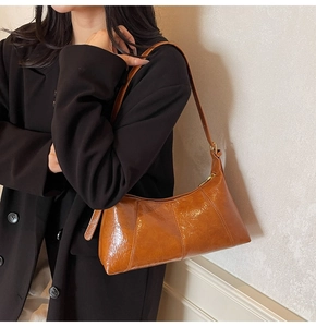 Détail du sac à bandoulière en cuir verni marron caramel avec garnitures métalliques dorées