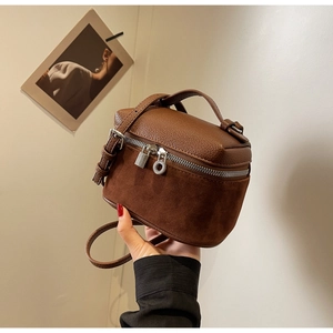 Detail of a mini two-tone brown box bag featuring pebbled leather and suede textures