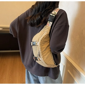 Detail of khaki nylon chest bag featuring a floral patterned wide strap on a model back