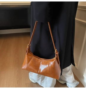 Détail du sac bandoulière marron brillant avec boucle en métal doré et finition lisse huilée