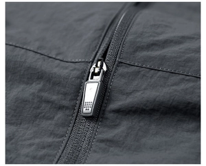 Detailed close-up of dark grey windproof jacket showing premium metal zipper with non-slip puller