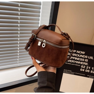 Close-up of retro brown crossbody box bag with mixed leather texture and metal lock charm
