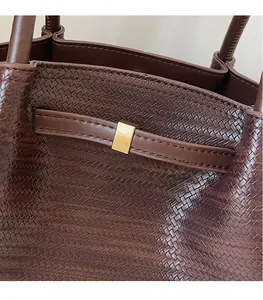 Detailed macro view of dark brown woven leather texture and golden metal buckle