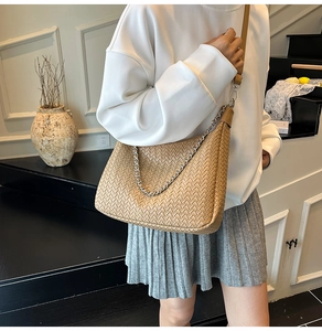 Detail of woven light brown crossbody bag with silver chain and adjustable shoulder strap