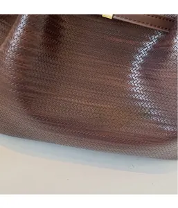 Detail shot of the luxury deep brown woven leather texture on a spacious shoulder bag