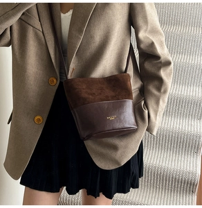 Detail of a brown patchwork bucket bag with suede texture and gold logo lettering