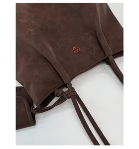 Detail view of dark brown faux leather tote with textured finish and mini pouch accessory