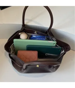 Deep brown tote bag with woven texture and smooth leather finish showing spacious interior