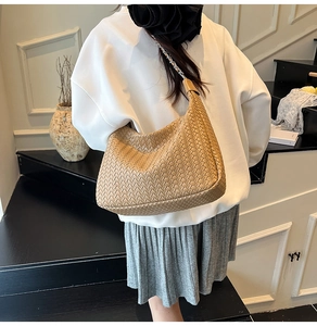 Detail of woven khaki shoulder bag with metal chain strap and leather padding