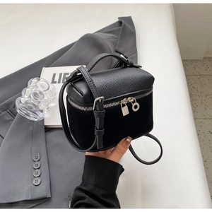 Detail of black pebbled leather crossbody bag with silver padlock and suede textures