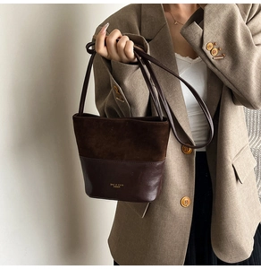 Detail of a brown patchwork bucket bag featuring suede and leather textures on a beige blazer