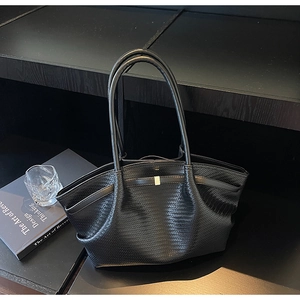 Close-up of black woven tote bag texture with elegant pleated design and long handles