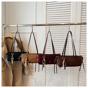 Detailed row of suede shoulder bags in black, tan, burgundy and coffee brown with tassels