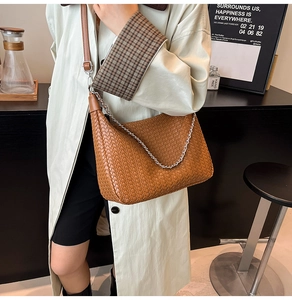 Detail of woven brown leather bag featuring silver metal chain and adjustable strap