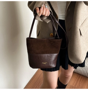 Close-up of the two-tone bucket bag with suede texture and gold logo lettering