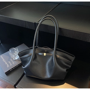 Close-up of black woven leather tote bag with elegant gold buckle and shoulder straps
