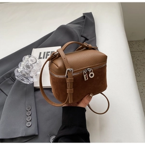 Detail of caramel leather box bag showing matte finish and metal zipper toggle